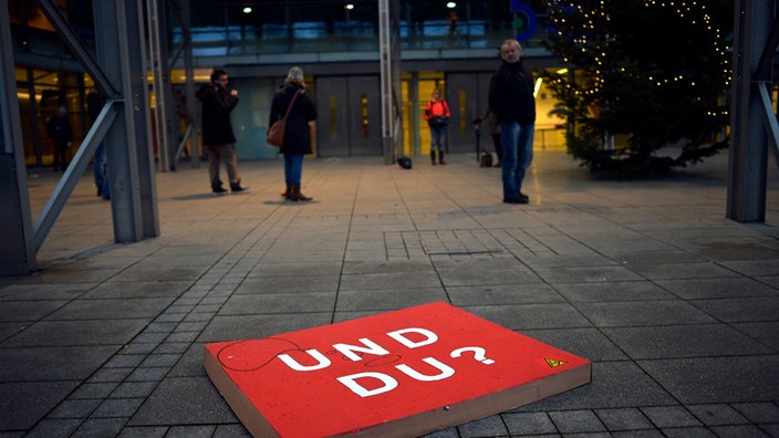 Ein Schild mit der Aufschrift Und Du? liegt vor Beginn einer Belegschaftsversammlung vor der Veranstaltungshalle