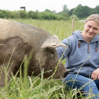 Eva Bird auf der Weide mit einem Schwein. 