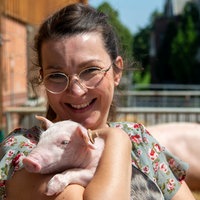 Nicole Nassiry mit einem Ferkel auf dem Arm.