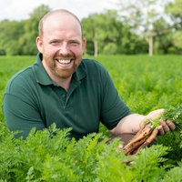 Rainer Overkämping mit einem Bund Möhren in der Hand.
