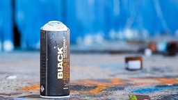 Eine leere Spraydose vor einer blauen Wand.