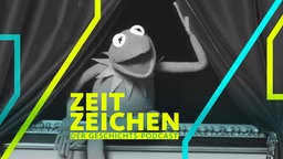 Kermit der Frosch öffnet den roten Vorhang eines Theaters