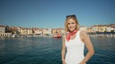 Stephanie Müller-Spirra in einer Hafenstadt vorm Wasser, im Hintergrund eine Hauslandschaft