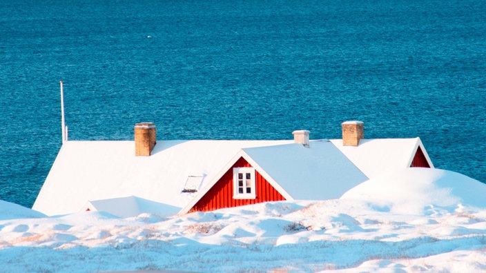 Das Dach eines roten Hauses ist über einem Eisberg zu sehen