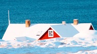 Das Dach eines roten Hauses ist über einem Eisberg zu sehen