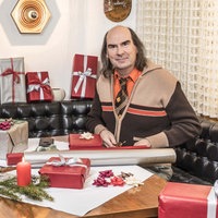 Guildo Horn sitzt an einem Tisch umringt von Geschenken und Geschenkpapier
