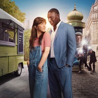 Eine Straße in Paris: In der Mitte des Bildes befinden sich Abel (Omar Sy) und Marion (Sara). Sie steht mit dem Rücken zu ihm, schaut ihn aber über die Schulter an, er schaut sie ebenfalls an. Fotografen im Hintergrund fotografieren das Paar.