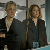 Szene aus der Thriller-Serie "Hundertdreizehn": Riccarda (gespielt von Anna Schudt, links) und Caro (gespielt Patricia Aulitzky) müssen ihren toten Partner identifizieren. Sie schauen durch ein Fenster in einer türkisen Tür.