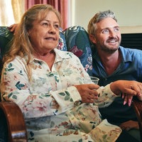 Filmszene aus dem Film "Noch einmal, June": June (Noni Hazlehurst) sitzt in einem grünen Sessel mit Blumenmuster. Rechts neben ihr befinden sich ihr Sohn Devon (Stephen Curry) und ihre Tochter Ginny (Claudia Karvan). June hält die Hand ihrer Tochter.