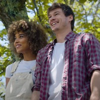 Szene aus dem Film " Zum Mars oder zu dir?": Daisy, gespielt von Alexandra Schipp, steht neben Alex, gespielt von Kyle Allen unter einem Baum. Durch die Baumkrone ist ein blauer Himmel zu sehen, beide scheinen auf etwas hinauszublicken und lächeln.
