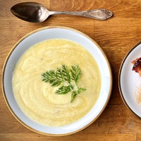 Ein Teller mit Kartoffelsuppe, daneben ein Teller mit einem Stück Pflaumenkuchen