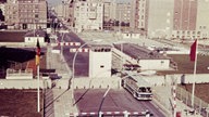 Ein Reisebus überquert einen Grenzübergang zwischen West- und Ost-Berlin. Laut dem Nutzer Carl Friedrich handelt es sich um "den ehemaligen Checkpoint Charlie."