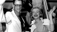 Marilyn Monroe und Arthur Miller winken vor einem Flugzeug der Presse zu