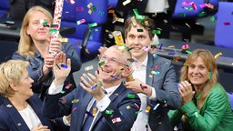 Abgeordnete der Grünen stehen in einem Konfetti-Regen und lachen ausgelassen