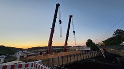 Zwei Kräne stehen bei Sonnenaufgang an der A4 bei Frechen-Königsdorf