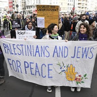 Eine Gruppe an Demonstranten läuft über die Straße mit einem Banner, auf dem steht "Palestinians and Jews for Peace"