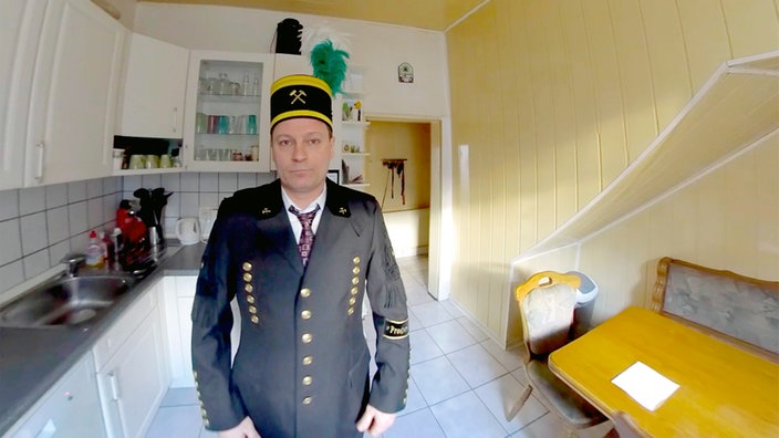 Der Steiger Andreas Schreiter steht in seiner Küche und trägt eine Traditionsuniform für Bergmänner