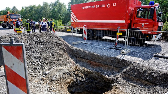 Feuerwehrfahrzeug und -einsatzkräfte an einem abgesperrten großen Loch in der Autobahn 45