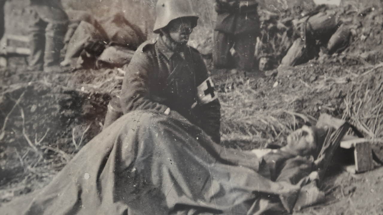 Ein Soldat liegt am Boden, ein anderer hockt neben ihm