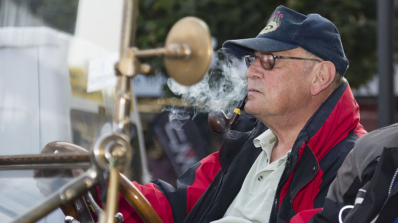 Walter Lippert sitzt Pfeife rauchend in seinem Oldtimer der Marke Overland
