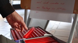 Mann nimmt eine rote Kerze aus einem Karton