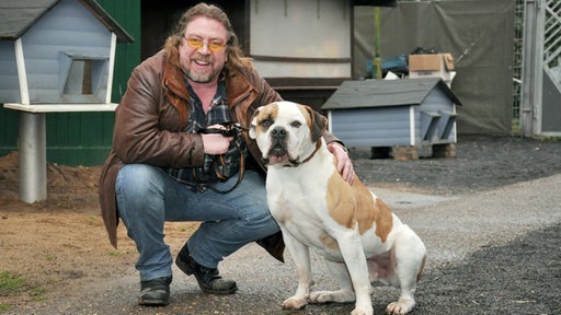 Armin Rohde kniet neben seinem Hund Ike