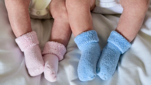 Zwei Babybeine mit jeweils rosa und blauen Söckchen