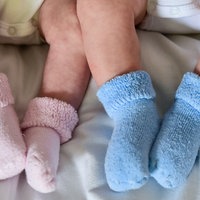 Zwei Babybeine mit jeweils rosa und blauen Söckchen