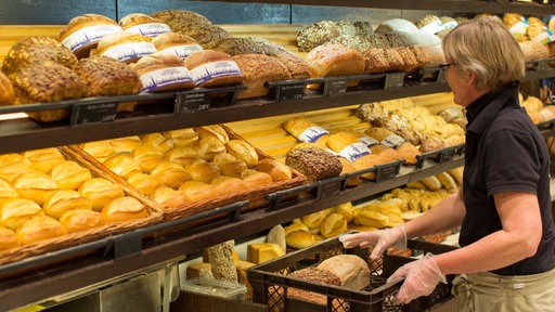 Bäckereiverkäuferin Petra Kortenkämper legt Brote in die Auslage einer Bäckerei