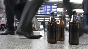 Drei Bierflaschen stehen an einem Bahnhof 