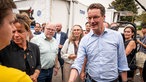 Nordrhein-Westfalens Ministerpräsident Hendrik Wüst (r, CDU), und Nordrhein-Westfalens Vize-Ministerpräsidentin und Wirtschaftsministerin Mona Neubaur (Grüne) unterhalten sich bei einem Besuch bei den Einsatzkräften des Waldbrands im Hürtgenwald.