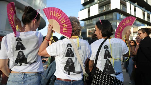 Vier Fans mit Celine Dion T-shirts und pinken Fächern stehen auf der Straße