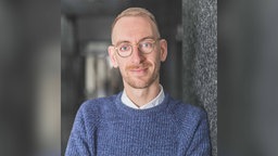 Christopher Wimmer lehnt an einer Hauswand
