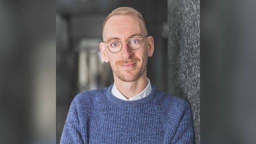 Christopher Wimmer lehnt an einer Hauswand