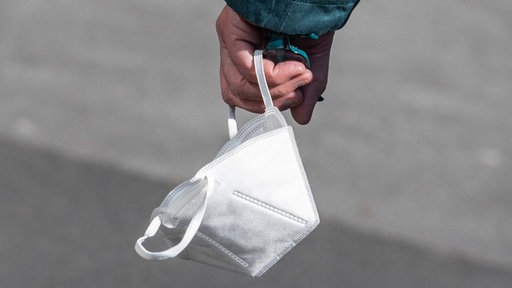 Person trägt eine FFP-2 Maske in der Hand