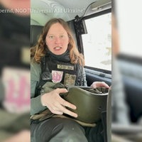Eine junge Frau sitzt in einem Auto und hat einen Stahlhelm auf dem Schoß