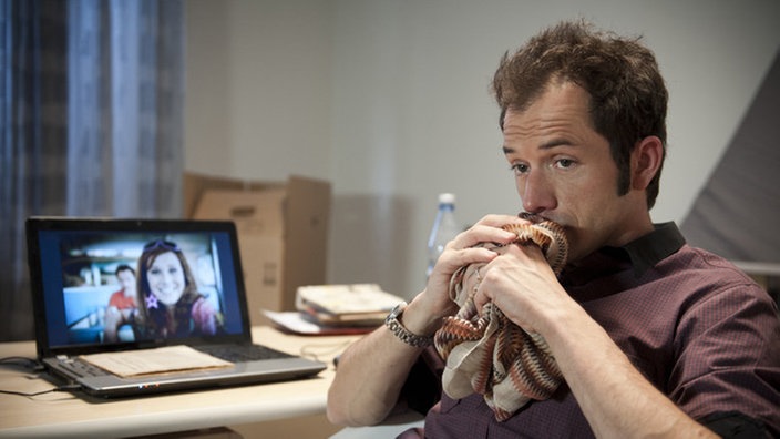 Alex sitzt traurig neben dem Laptop mit Bildern von Josi