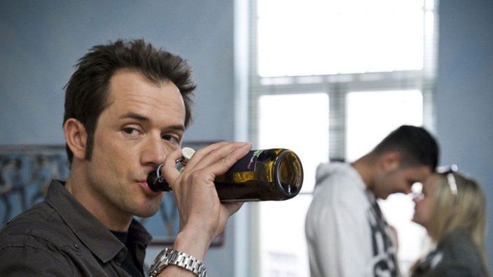 Alex trinkt genervt Bier