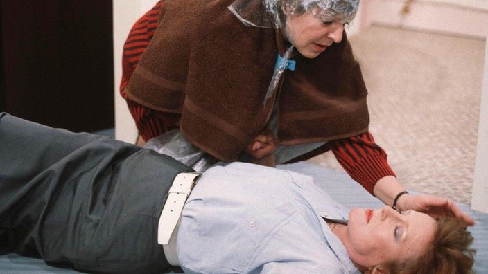 Als Isolde (Marianne Rogée) Nachricht vom Tod ihres Mannes erhält, bricht sie zusammen. Helga (Marie-Luise Marjan, links) versucht ihr zu helfen.