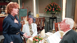 Amélie (Anna Teluren) und Priesnitz (Carlos Werner) lassen sich von Isolde (Marianne Rogée, links) bei der Menuwahl beraten.