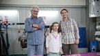 Andy, Gabi und Antonia stehen in der Werkstatt vor dem Camaro