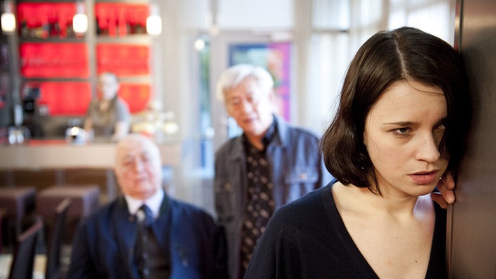 Angelina lehnt sich an eine Wand im "Café George"