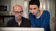 Angelina schaut mit Philipp auf einen Bildschirm