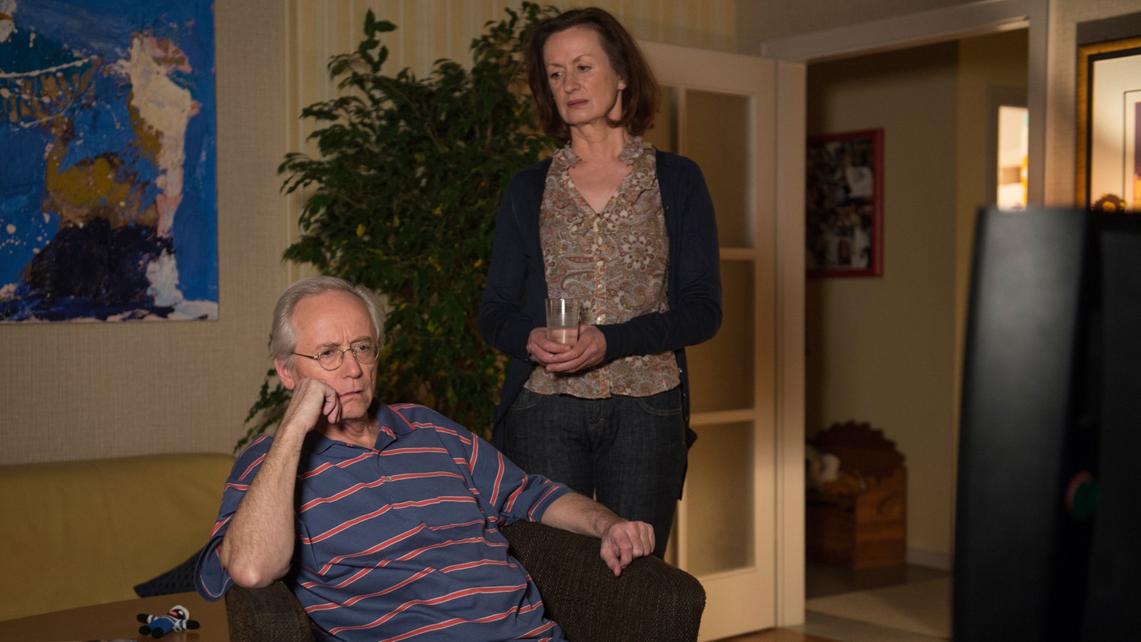 Anna bringt dem grummeligen Hans ein Glas
