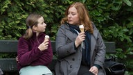 Antonia und Iffi sitzen auf einer Bank und essen Eis