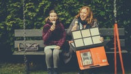 Antonia und Iffi sitzen auf einer Bank und essen Eis