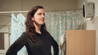 Beate (Susanne Gannott) hat in den Lautsprechern heimlich Kameras installiert, mit denen sie das Geschehen in der Wohngemeinschaft einfängt und ins Internet überträgt.