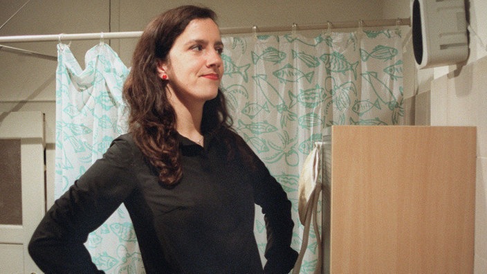 Beate (Susanne Gannott) hat in den Lautsprechern heimlich Kameras installiert, mit denen sie das Geschehen in der Wohngemeinschaft einfängt und ins Internet überträgt.