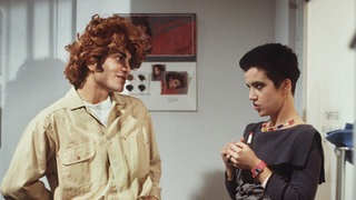 Beate (Susanne Gannott) und Vasily (Hermes Hodolides) flirten albern im Friseursalon.