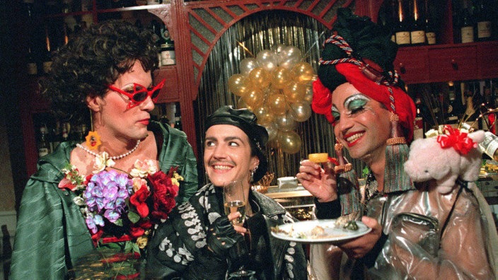 Carsten (Georg Uecker, links), "Käthe" (Claus Vinçon) und Beate (Susanne Gannot) haben sich für die Party im "Casarotti" verkleidet.
